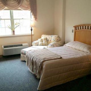 A cozy bedroom with a single bed, chair, and window providing natural light.