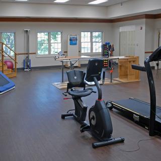 A rehabilitation center featuring various exercise equipment including a treadmill and stationary bike.