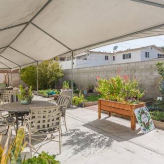 A covered outdoor patio area with tables, chairs, and raised garden beds.