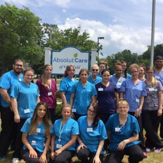 A group of healthcare workers in uniform gathered outside near a sign.