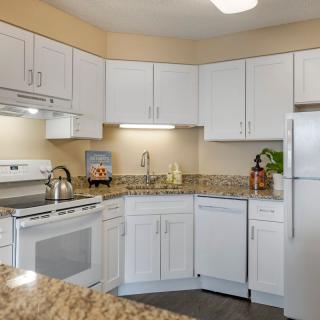 A modern kitchen with white cabinets and granite countertops.