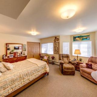 A cozy bedroom with a comfortable bed, armchairs, and warm lighting.