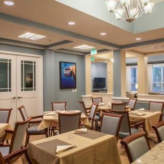 A well-lit dining room with neatly arranged tables and chairs.