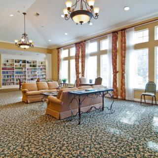 A cozy library reading room featuring a sofa, table, and bookshelves with large windows.