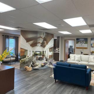A modern office interior featuring a lounge area with stylish furniture and bright lighting, complemented by a decorative wall mural.