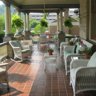 A spacious porch with wicker furniture and potted plants, offering a comfortable outdoor seating area.