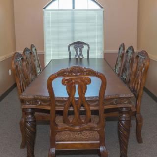 A classic wooden dining set with a table and six chairs in a well-lit room.