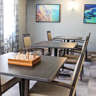 A modern game room with chess set on the table, surrounded by chairs and artistic wall decor.