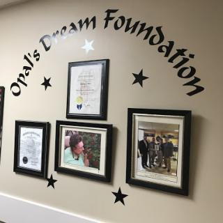 A display featuring Opal's Dream Foundation with framed photos and certificates on the wall.
