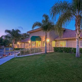 A serene evening view of a house surrounded by palm trees and a well-maintained yard.