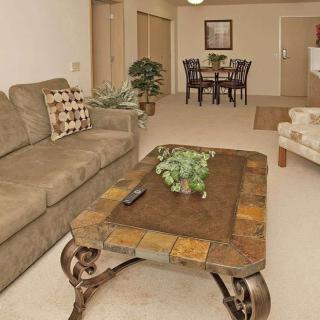 A cozy living room with a sofa and coffee table leading to a dining area in the background.