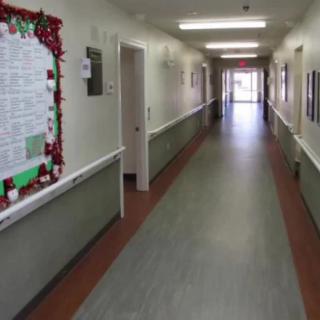 A long hallway with a decorated notice board on the wall.