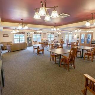 A spacious community dining area featuring wooden tables and chairs, illuminated by warm light fixtures.