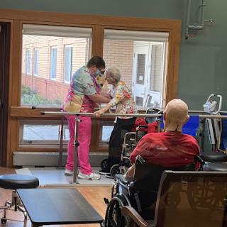 A healthcare professional assists an elderly patient in a rehabilitation setting, showcasing the attentive care provided in senior living facilities.
