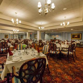 A spacious and elegantly decorated dining room with set tables and ornate chandeliers.