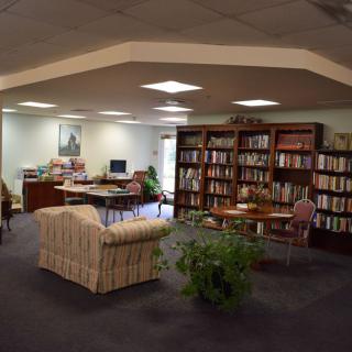 A cozy library reading area with bookshelves, seating, and a computer desk.