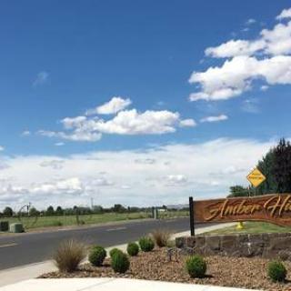 A scenic view of a neighborhood entrance with a clear sky and scattered clouds.
