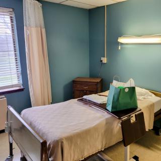 A calm and clean hospital room featuring a bed, storage, and natural light.