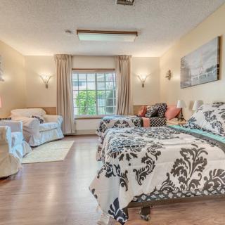 A cozy and stylish bedroom featuring double beds with elegant bedding, a large window, and comfortable seating.