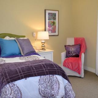 A cozy bedroom with colorful bedding and a well-lit lamp on the nightstand.