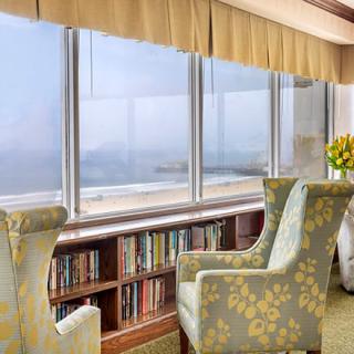 A cozy reading nook with comfortable chairs and bookshelves overlooking a scenic view through large windows.