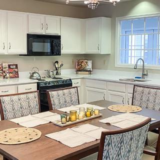 A modern kitchen with a dining area featuring white cabinets and sleek appliances.