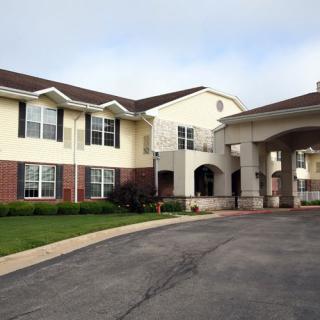 A two-story residential building with an arched entrance and a paved driveway.
