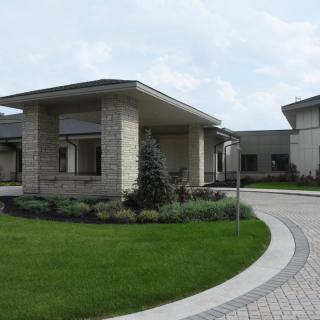 A modern building with a circular driveway and landscaped greenery.