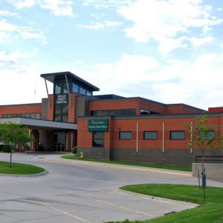A view of a hospital building with an entrance and surrounding greenery.