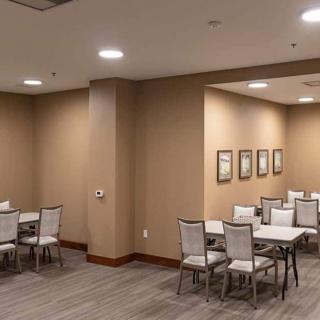 An empty conference room with tables and chairs arranged neatly, adorned with wall art.