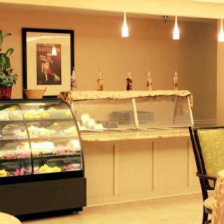 An inviting bakery with a well-lit cake display and comfortable seating area.