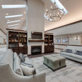 A modern living room with elegant furniture, a central fireplace, and natural light from skylights.