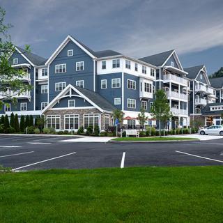 A modern residential apartment complex with a large parking area and well-maintained landscaping.