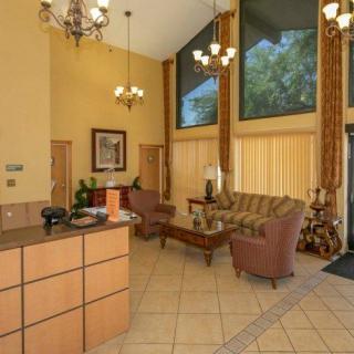 A hotel lobby with a reception desk, elegant chandeliers, and comfortable seating area.