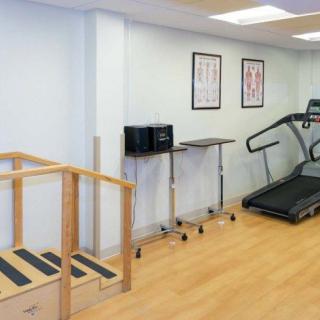 A physical therapy room equipped with a treadmill and a set of stairs for rehabilitation exercises.
