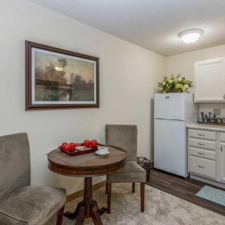 A small kitchen and dining area featuring a round table with two chairs, a refrigerator, and decorative elements.