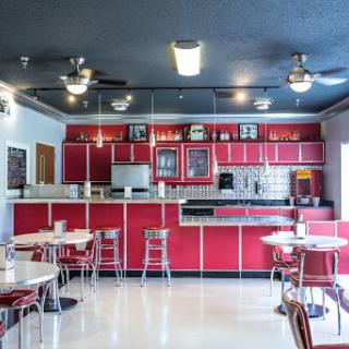 A vibrant retro diner kitchen with striking red cabinetry and classic furniture.
