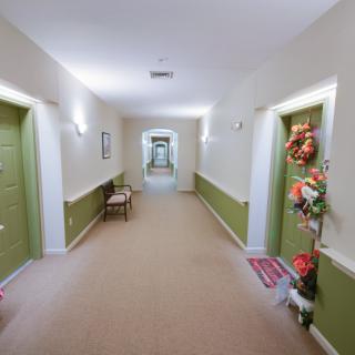 A brightly lit hallway with doors on either side, some decorated with flowers.