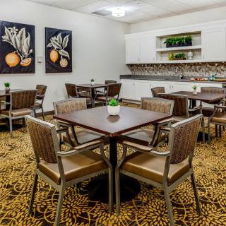 A modern dining area with neatly arranged tables and chairs, featuring artwork on the walls.