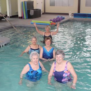 A group of women participating in an aquatic exercise class at an indoor pool.