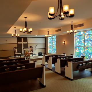 Interior view of a peaceful chapel with wooden pews and stained glass windows.