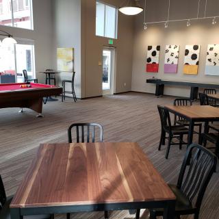 A modern interior space with tables, chairs, a pool table, and colorful artwork on the walls.