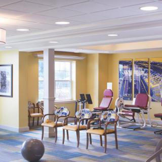 A well-lit exercise and rehabilitation room with gym equipment and seating.