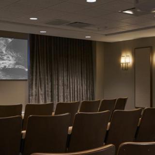 An empty theater room with a projection screen displaying an image.