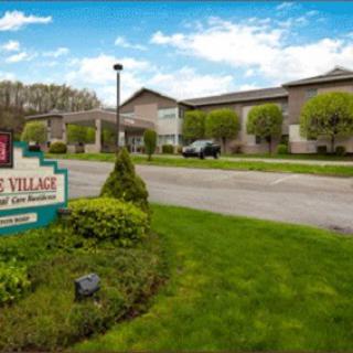 A welcoming entrance to a charming village, surrounded by lush greenery and a bright blue sky.