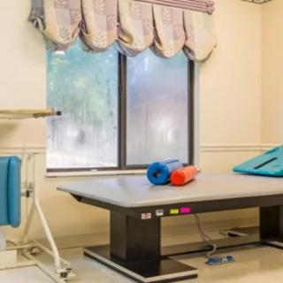 A therapy room featuring a treatment table and exercise equipment by the window.