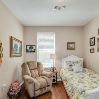 A cozy bedroom with a single bed, armchair, and decorative wall art.