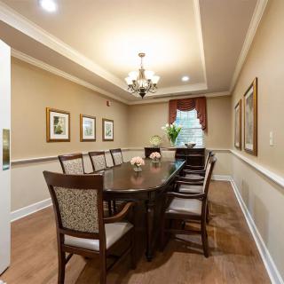 A neatly arranged dining room with a long table, surrounded by chairs and illuminated by a chandelier.