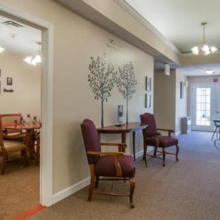 A well-lit hallway featuring elegant chairs and decorative wall art.
