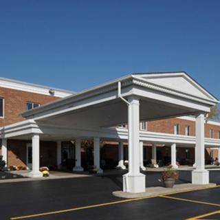 A commercial building with a grand entrance featuring columns and a paved parking area.